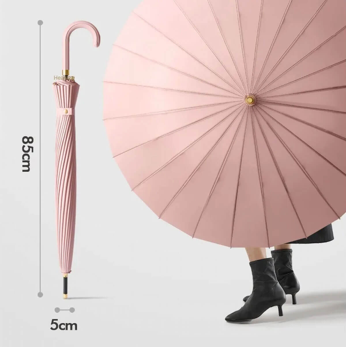 Pink luxury umbrella for women leaning against designer handbag for size comparison