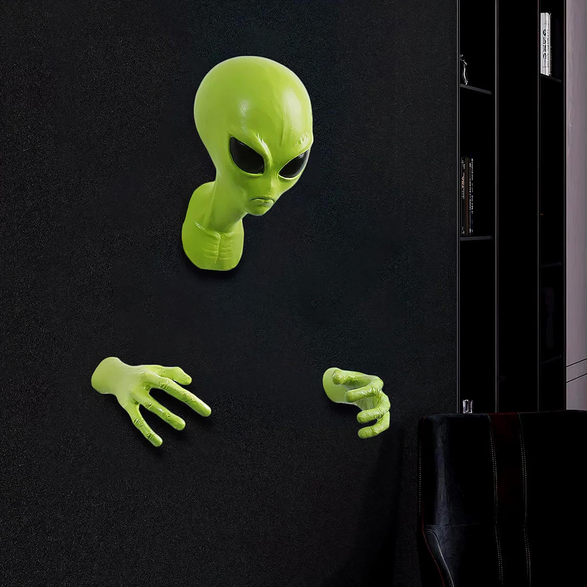 Green alien wall sculpture breaking through black wall