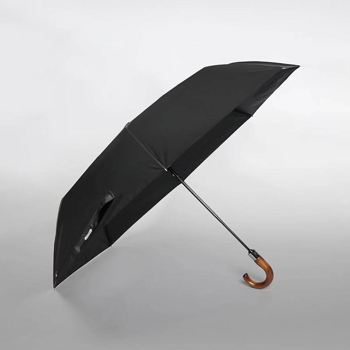 Person holding large folding umbrella, displaying comfortable wooden grip