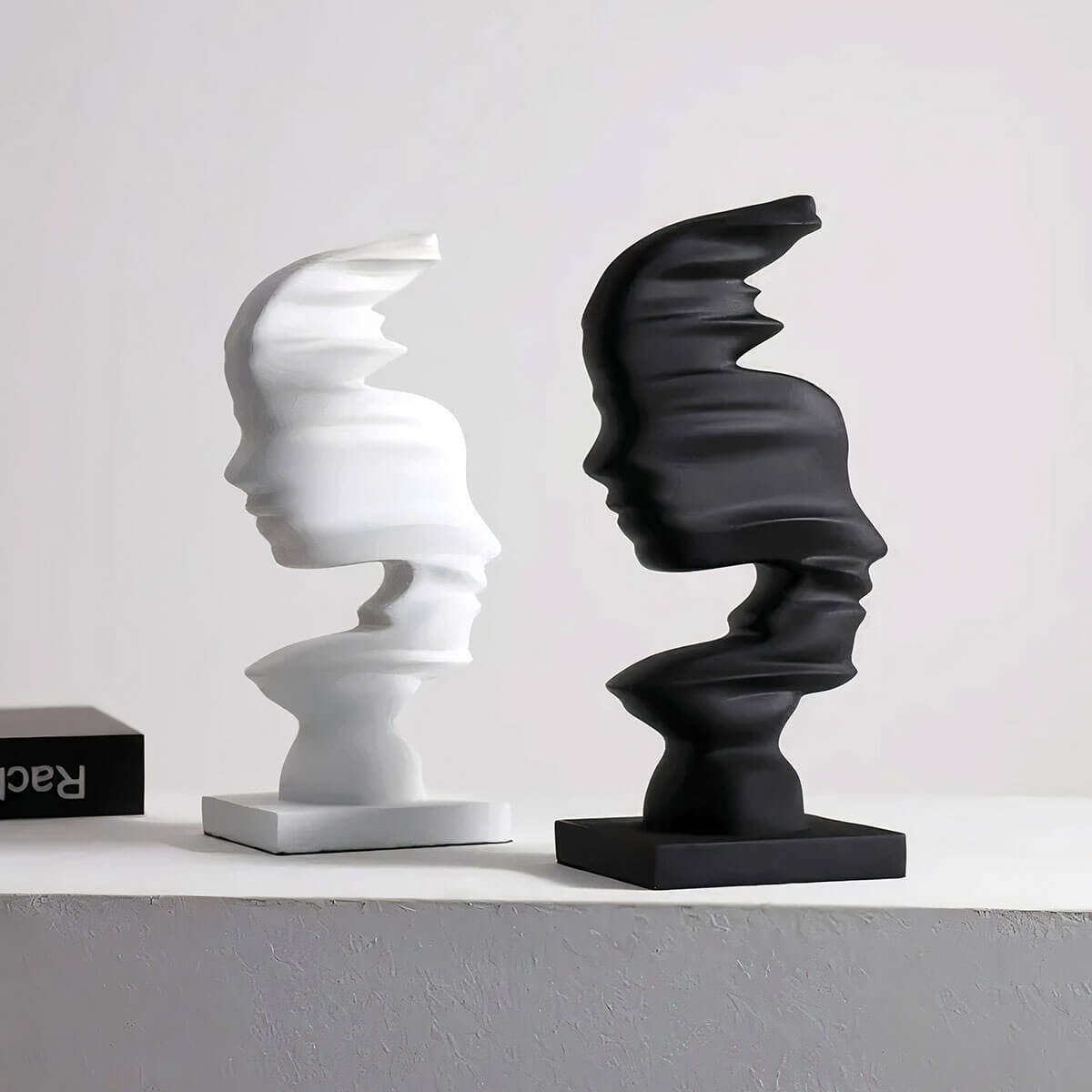 Abstract black modern art sculpture depicting male and female faces