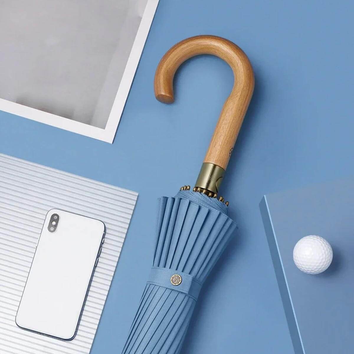 Person showcasing the large size of open blue wooden handle umbrella